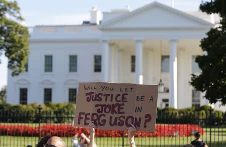 A protesters holds a sign calling for a thorough investigation of the shooting death of teen Michael Brown in Ferguson, Missouri, on a street in front of the White House in Washington, August 28, 2014. REUTERS/Larry Downing