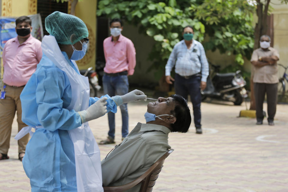 A health worker takes a nasal swab sample of a man at an urban health centre in Ahmedabad, India, Thursday, July 16, 2020. India's virus cases surged another 32,695 as of Thursday, taking the nation closer to 1 million and forcing a new lockdown in the popular western beach state of Goa two weeks after it was reopened to tourists. (AP Photo/Ajit Solanki)