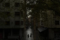 Pedestrian shelters from the rain under an umbrella while walking along the old city during a raining autumn day, in Pamplona, northern Spain, Saturday, Oct. 3, 2020. (AP Photo/Alvaro Barrientos)