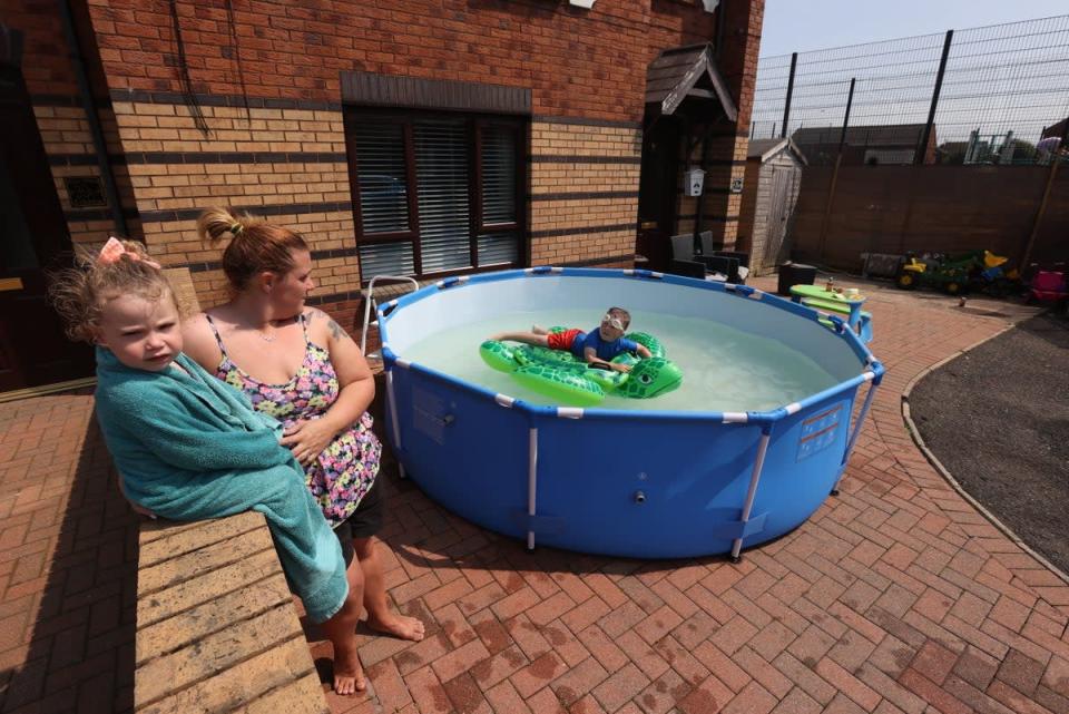 Emma Stewart with her children cooling down in a swimming pool at their family home in Ardoyne (Liam McBurney/PA) (PA Wire)