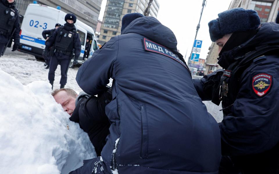 Police officers detain a man during a gathering in memory of Russian opposition leader Alexei Navalny near the Wall of Grief monument