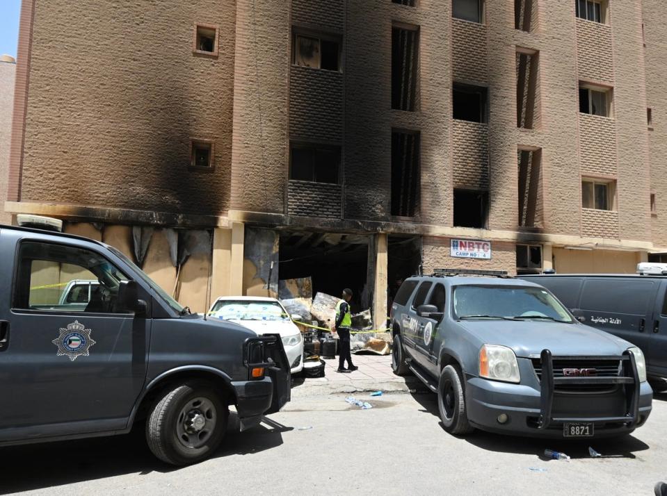 A Kuwaiti policeman stands in front of a residential building after a fire broke out in Mangaf area, southern Ahmadi governorate, Kuwait, 12 June 2024 (EPA)