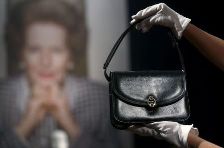 An employee holds a navy blue leather handbag, part of the collection of former British prime minister Margaret Thatcher during an auction preview at Christie's in London, Britain, December 11, 2015. REUTERS/Peter Nicholls