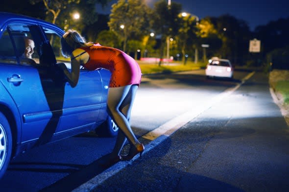 Young prostitute wearing red propositions man in car