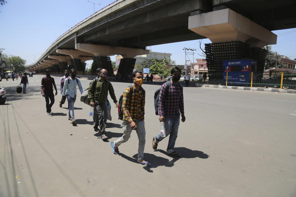 Migrant laborers from other states walk through a deserted road during a curfew as a precautionary measure against COVID-19 in Jammu, India, Sunday, April.25, 2021. (AP Photo/Channi Anand)