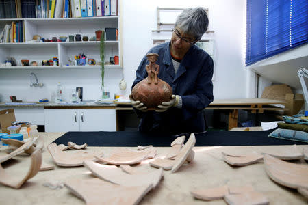 Conservationist Elisheva Kamaisky, shows journalists a 3,800 year-old pottery jug with a rare statuette, discovered during excavation in central Israel, at the Israel Antiquities Authority offices in Jerusalem November 23, 2016. REUTERS/Ammar Awad