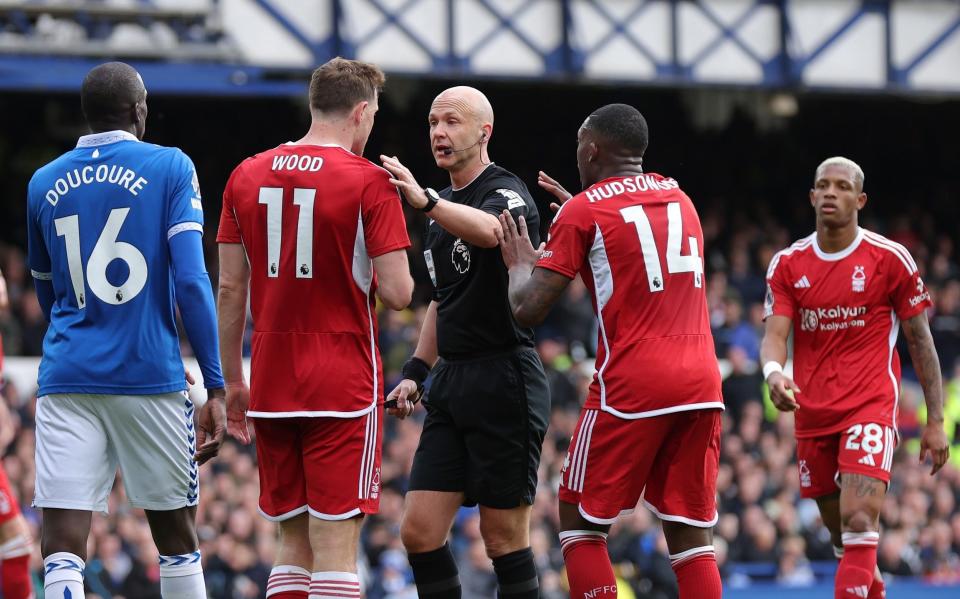 Referee Anthony Taylor is confronted by Chris Wood and Callum Hudson-Odoi of Nottingham Forest claiming a handball against Ashley Young of Everton (not pictured) during the Premier League match between Everton FC and Nottingham Forest at Goodison Park on April 21, 2024 in Liverpool , England