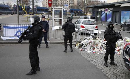 An Israeli flag hangs on a barricade as special French forces secure the area for the visit by Israel's Prime Minister Benjamin Netanyahu to the Hyper Cacher kosher supermarket January 12, 2015 near the Porte de Vincennes in Paris, where four hostages were killed in a terror attack on Friday. Jewish schools and synagogues in France have been promised extra protection, by the army if necessary, after killings by Islamic militants in Paris, the head of the community's umbrella group said on Sunday after a meeting with the French President. REUTERS/Charles Platiau