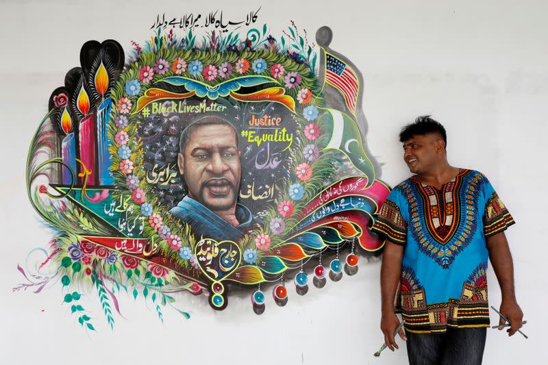 FILE PHOTO: Pakistani truck-art painter Haider Ali, 40, poses for a photograph next to a mural, depicting George Floyd, who died in Minneapolis police custody in U.S., in Karachi