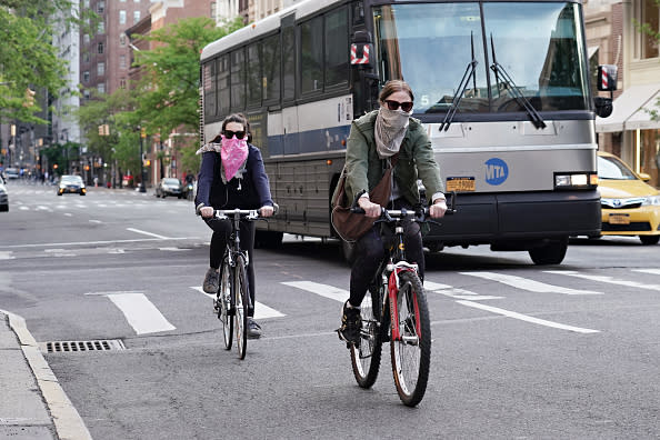 People ride bikes while wearing face coverings during the coronavirus pandemic in New York City. 