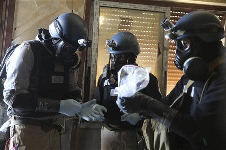 A U.N. chemical weapons expert, wearing a gas mask, holds a plastic bag containing samples from one of the sites of an alleged chemical weapons attack in the Ain Tarma neighbourhood of Damascus in this August 29, 2013 file photo. REUTERS/Mohamed Abdullah/Files