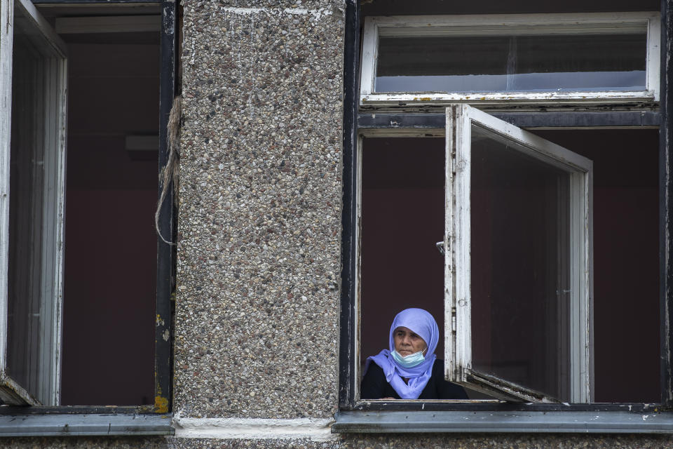 An Iraqi woman looks from a window of a building at the refugee camp in the village of Verebiejai, some 145km (99,1 miles) south from Vilnius, Lithuania, Sunday, July 11, 2021. Migrants at the school in the village of Verebiejai, about 140 kilometers (87 miles) from Vilnius, haven't been allowed to leave the premises and are under close police surveillance. Some have tested positive for COVID-19 and have been isolated in the building. (AP Photo/Mindaugas Kulbis)