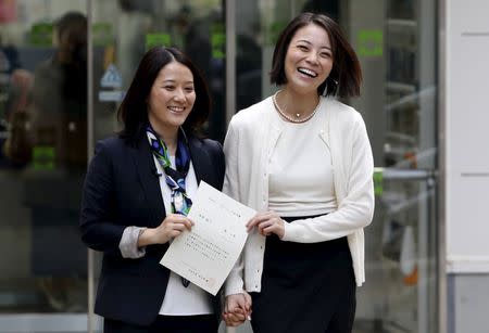 Hiroko Masuhara (L) and her partner Koyuki Higashi hold their partnership certificate as they walk out from the Shibuya ward office after the ward office issued the nation's first same sex partnership certificates in Tokyo, Japan, November 5, 2015. REUTERS/Yuya Shino