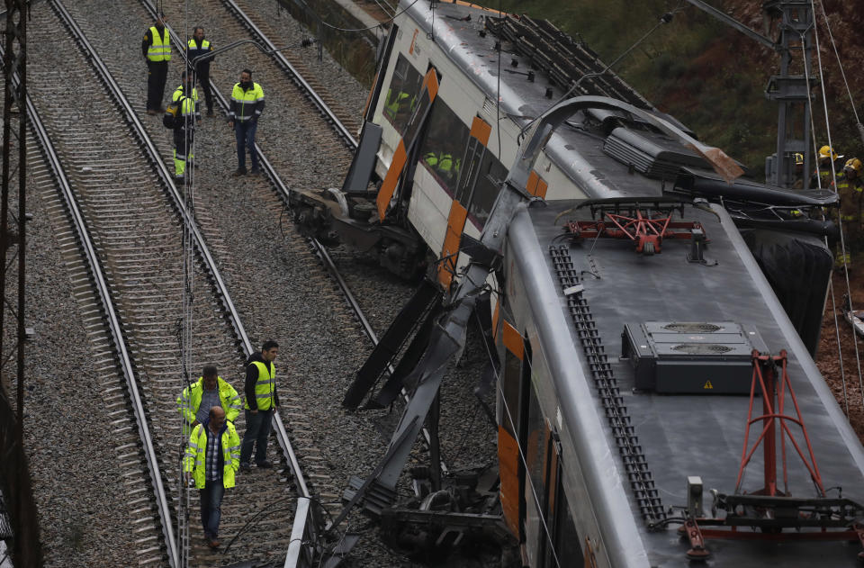 Firefighters and emergency workers stand by the derailed cars of a commuter train that went off the tracks near Barcelona, Spain, Tuesday, Nov. 20, 2018. Authorities in Spain say one person has died and six have been slightly injured when a landslide derailed the commuter train traveling toward Barcelona early on Tuesday. (AP Photo/Emilio Morenatti)