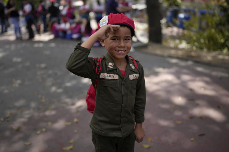 A boy dressed as late Venezuelan President Hugo Chavez salutes as he stands in line to visit Chavez's tomb during commemorations marking the tenth anniversary of his death, outside the Cuartel de la Montaña 4F in Caracas, Venezuela, Sunday, March 5, 2023. Chavez died on March 5, 2013, after a long battle with cancer and chose current president, Nicolas Maduro, a former bus driver and union leader to be his successor. (AP Photo/Ariana Cubillos)