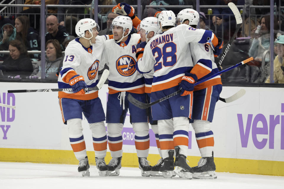 New York Islanders center Mathew Barzal (13) celebrates with right wing Cal Clutterbuck (15), second from left, center Casey Cizikas (53), third from left, defenseman Alexander Romanov (28) and others after Cizikas' goal against the Seattle Kraken during the second period of an NHL hockey game Thursday, Nov. 16, 2023, in Seattle. (AP Photo/John Froschauer)