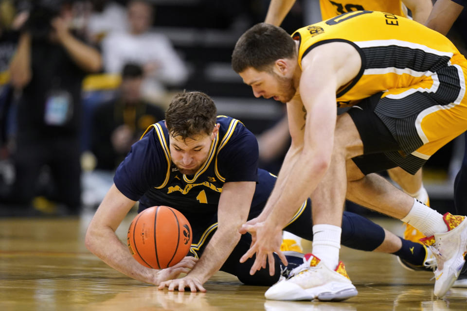 Michigan center Hunter Dickinson, left, fights for a loose ball with Iowa forward Filip Rebraca during the second half of an NCAA college basketball game, Thursday, Jan. 12, 2023, in Iowa City, Iowa. Iowa won 93-84 in overtime. (AP Photo/Charlie Neibergall)