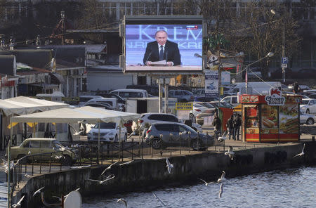 A screen, showing Russian President Vladimir Putin's annual end-of-year news conference, is on display on an embankment of the Black Sea port of Sevastopol, Crimea, December 17, 2015. REUTERS/Pavel Rebrov/File Photo