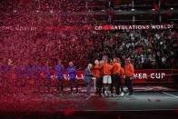 Team World's members celebrate with the trophy, watched by Australian tennis legend Rod Laver and members of Team Europe at the end of the Laver Cup tennis tournament in London, Sunday, Sept. 25, 2022. (AP Photo/Kin Cheung)