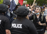 FILE - A participant in a protest over the death of George Floyd squares off with Denver Police officers Friday, May 29, 2020, in Denver. The massive protests sweeping across U.S. cities following the police killing of a black man in Minnesota have elevated fears of a new surge in cases of the coronavirus. Images showing thousands of screaming, unmasked protesters have sent shudders through the health community, who worry their calls for social distancing during the demonstrations are unlikely to be heard. (AP Photo/David Zalubowski)