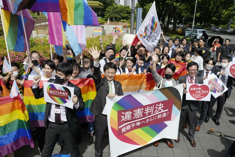 People including plaintiffs' lawyers hold banners and flags after the lower court ruled that not allowing same-sex marriage was unconstitutional outside Nagoya district court