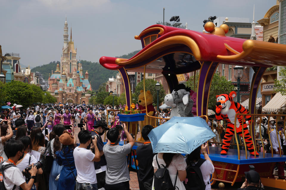 Visitors take photographs of cartoon characters during a parade at the Hong Kong Disneyland, Thursday, April 21, 2022. Hong Kong Disneyland reopened to the public after shutting down due to a surge in COVID-19 infections. (AP Photo/Kin Cheung)