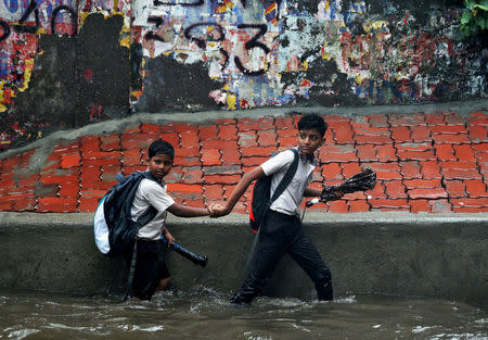 School children wade through a waterlogged street after heavy rains in Mumbai, July 3, 2018. REUTERS/Francis Mascarenhas