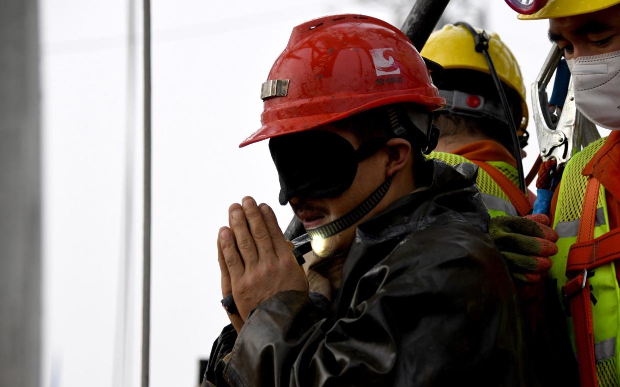 A blindfolded miner expresses holds his hands together in gratitude for his rescue - Xinhua/Shutterstock