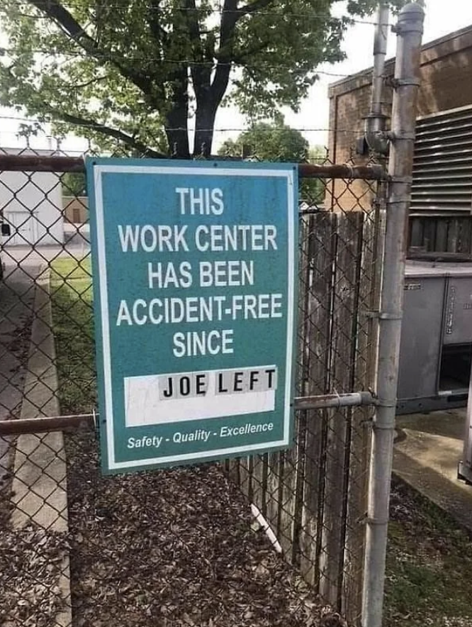 Sign reads, "This work center has been accident-free since Joe left." Below, it says, "Safety • Quality • Excellence." Sign is on a chain-link fence