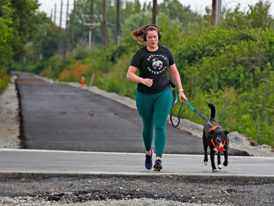 Rachel Stoneking runs with her dog Zika on the Nickel Plate Trail in Fishers, Wednesday, July 22, 2020.  This was there first time on the trail.  Stoneking says she likes the trail because she can run with him and he can have space to run around her without getting on the road.  A 1-mile portion of the trail from North Street to 126th Street has been paved.  It's technically not open but people are already using it.  The city says that is okay.