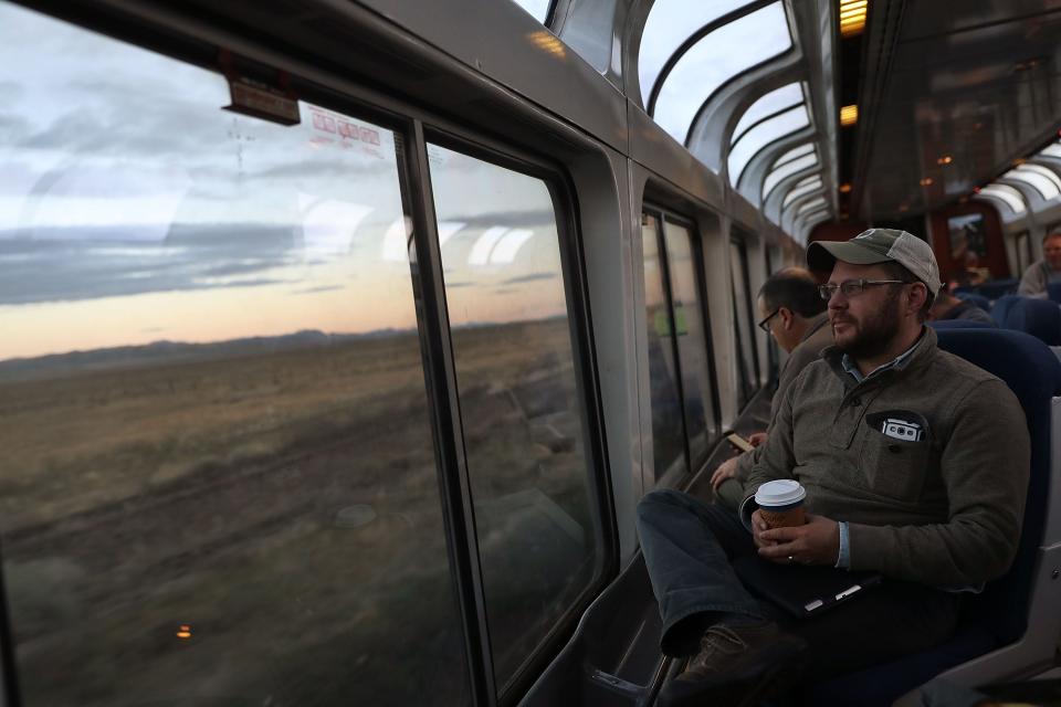 A man looking out of the  sightseer lounge car on a train.