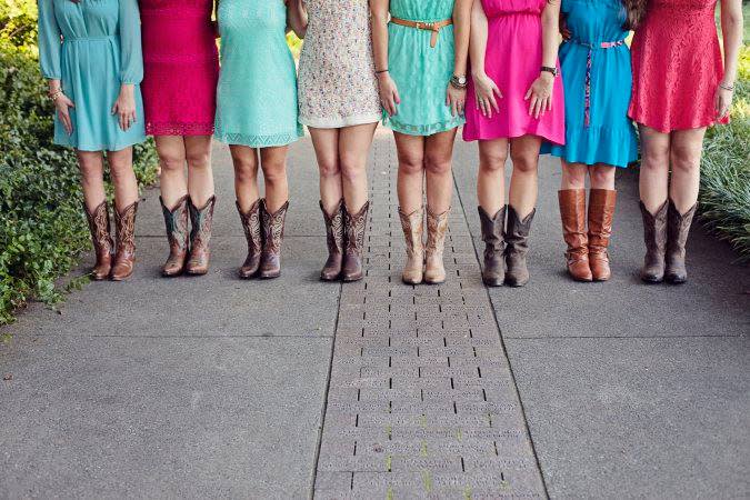 A line of attendees at a bachelorette party in colorful dresses and cowboy boots