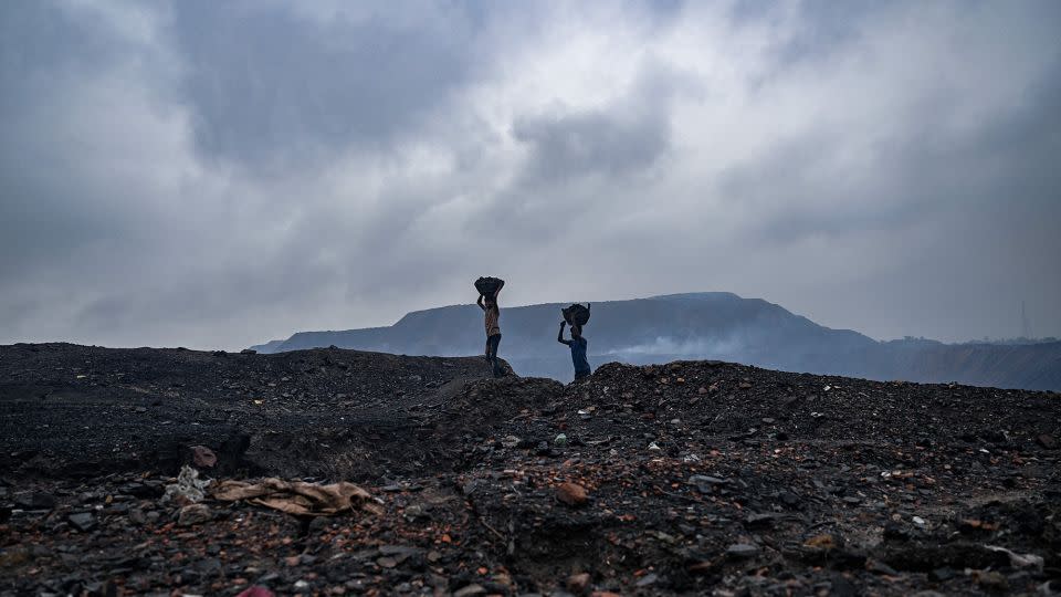 Coal pickers carry coal from near an open cast mining site on the outskirts of Dhanbad on July 6, 2023. India expects to double coal output by 2030. - Money Sharma/AFP/Getty Images