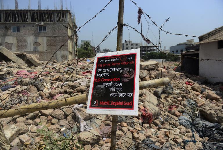 A poster tied to a fence at the scene of the Bangladesh Rana Plaza building collapse reads, "We want a safe work place, not a death trap' on the first anniversary of the disaster on the outskirts of Dhaka on April 24, 2014