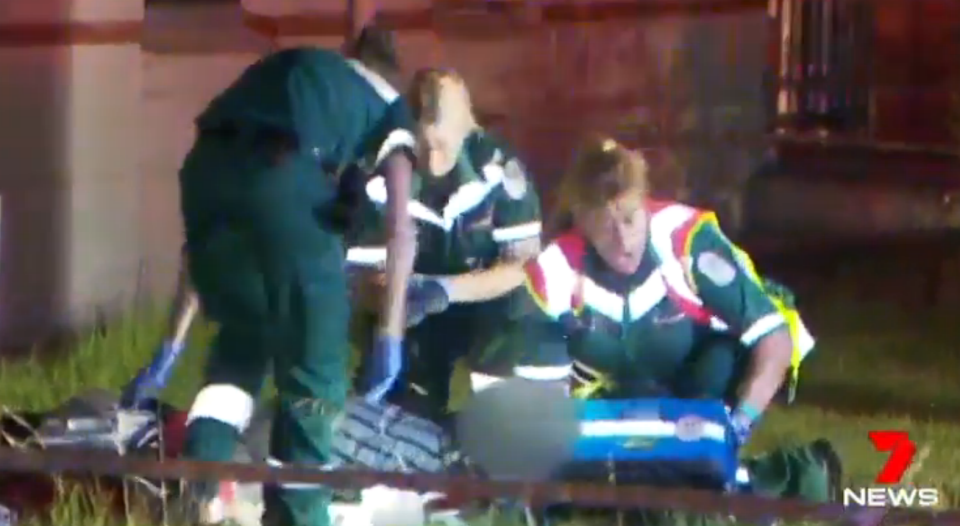 Paramedics treat the man outside of the burning house. Source: 7 News