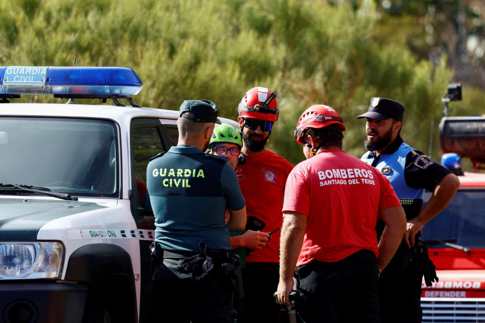 Police officers and firefighters talk during the search for a young British man in the Masca ravine, on the island of Tenerife. Spain, June 19, 2024. REUTERS/Borja Suarez