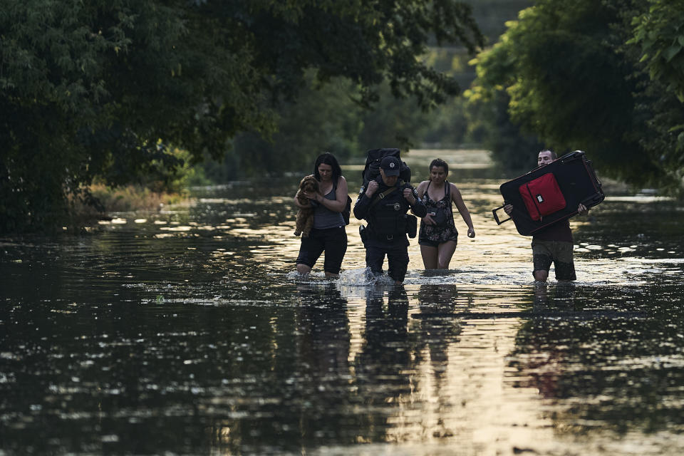 Local residents carry their belongings as they evacuated from a flooded neighborhood in Kherson, Ukraine, Tuesday, June 6, 2023. The wall of a major dam in a part of southern Ukraine has collapsed, triggering floods, endangering Europe's largest nuclear power plant and threatening drinking water supplies. (AP Photo/Libkos)