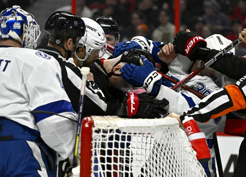Tampa Bay Lightning left wing Brandon Hagel (38) tries to rip the helmet off Ottawa Senators left wing Brady Tkachuk as they tussle after a whistle around the net of Lightning goaltender Brian Elliott (1) during second-period NHL hockey game action in Ottawa, Thursday, March 23, 2023. (Justin Tang/The Canadian Press via AP)