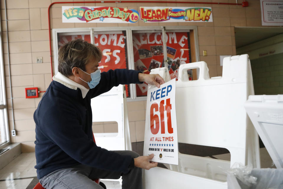 Joshua Ramos, an election technician with the Baltimore City Board of Elections, prepares signs at a polling center ahead of the 7th Congressional District special election at Edmondson High School, Monday, April 27, 2020, in Baltimore. Democrat Kweisi Mfume and Republican Kimberly Klacik won special primaries for the Maryland congressional seat that was held by the late Elijah Cummings. The high school is one of three places where residents will be allowed to vote in person in an effort to contain the spread of the new coronavirus. (AP Photo/Julio Cortez)