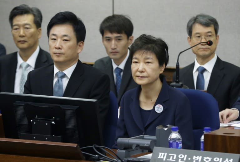 The ousted president was brought to court in handcuffs, wearing a blue trouser suit and a badge with her prisoner number