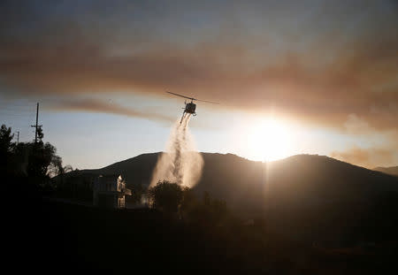 A helicopter drops water as the Woolsey Fire continues to burn in Malibu, California, U.S. November 10, 2018. REUTERS/Eric Thayer