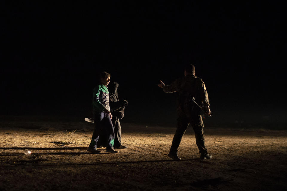 A U.S.-backed Syrian Democratic Forces (SDF) fighter, right, guides a woman and boy that were evacuated out of the last territory held by Islamic State militants at a screening center outside Baghouz, Syria, Monday, Feb. 25, 2019. (AP Photo/Felipe Dana)