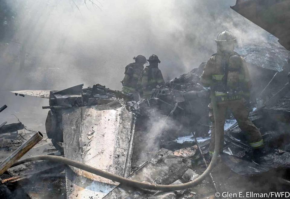 Firefighters respond to the scene where a Navy plane crashed behind a home in Lake Worth, Texas on Sunday, Sept. 19, 2021.