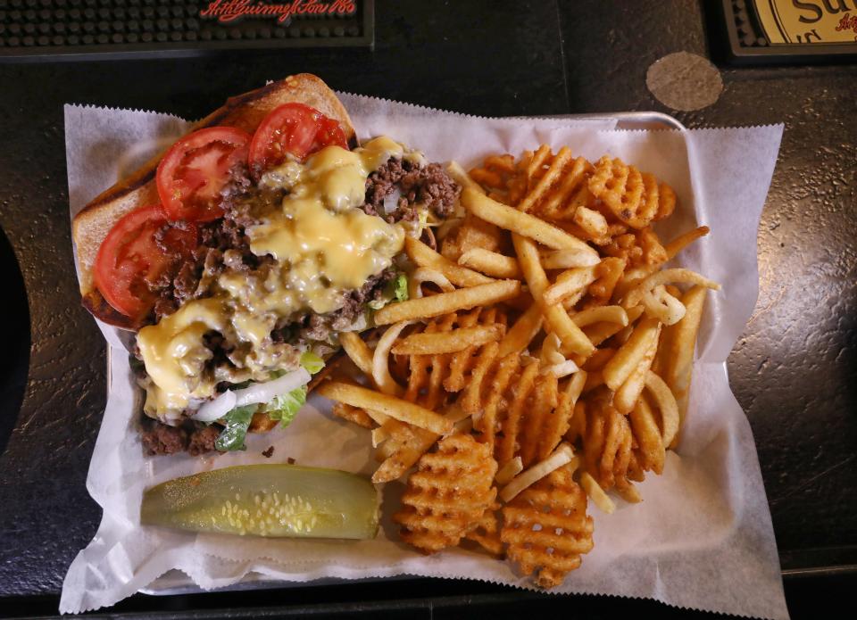 The Chopped Cheese sandwich, served with a side of fries and a pickle.