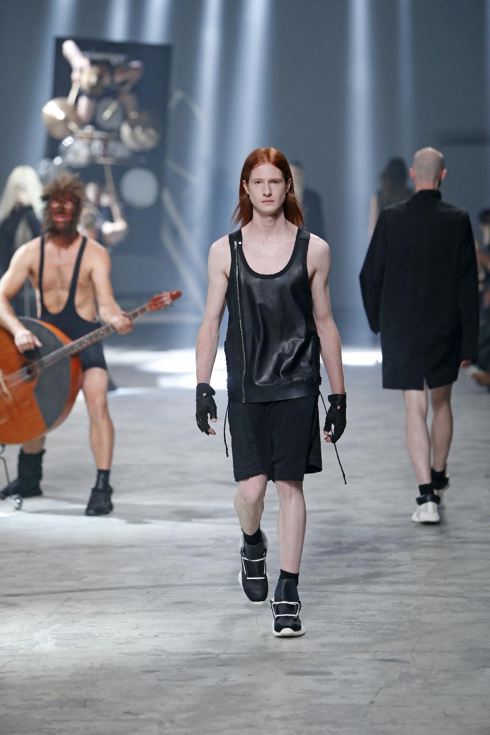 A model wears a creation by fashion designer Rick Owens as part of his men's fashion Spring-Summer 2014 collection, presented Thursday, June 27, 2013 in Paris, as Estonian metal/punk band Winny Puhh perform live, rear left. (AP Photo/Francois Mori)