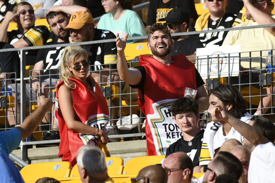 A pair of fans wear ketchup bottle costumes as they move through the stands at Acrisure Stadium during the first half of an NFL preseason football game between the Pittsburgh Steelers and the Detroit Lions, Sunday, Aug. 28, 2022, in Pittsburgh. (AP Photo/Don Wright)