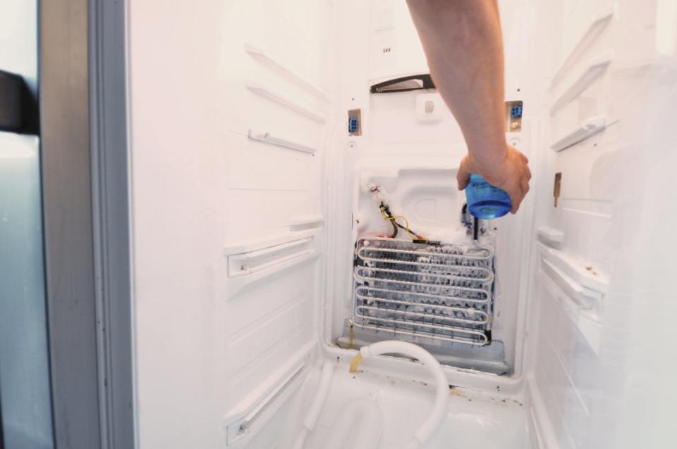 Person cleaning fridge coil with spray