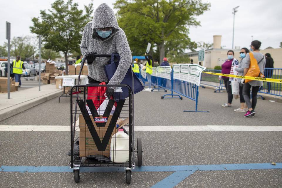 In this Thursday, May 28, 2020, photo, Maria G.'s checks the groceries she was given during a food distribution drive sponsored by Island Harvest Food Bank in Valley Stream, N.Y. The Valley Stream stream donations were just one of many events Island Harvest has conducted throughout the area recently. (AP Photo/Mary Altaffer)