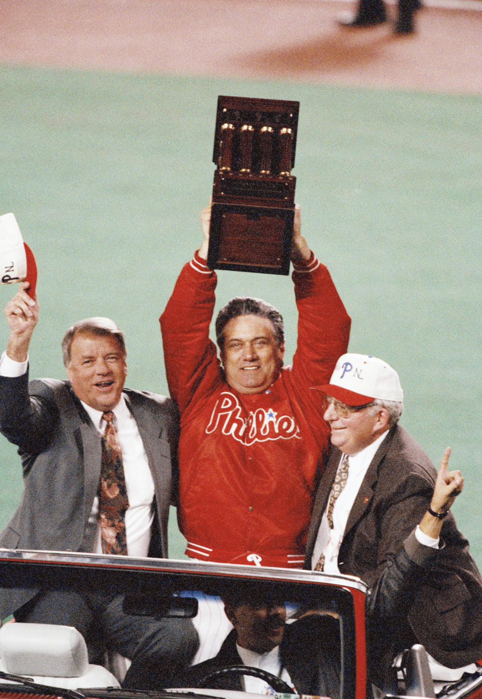 FILE - Philadelphia Phillies manager Jim Fregosi, center, holds up the NL Championship trophy as Phillies general manager Lee Thomas, left, and Phillies President Bill Giles look on during their drive around the field after the Phillies 6-3 win over the Atlanta Braves in Game 6 of the NL Playoffs, Oct. 14, 1993, Philadelphia, Pa. Lee Thomas, an All-Star player who eventually became the architect of the 1993 National League champion Philadelphia Phillies, has died. He was 86. Thomas died Wednesday, Aug. 31, 2022, at his home in St. Louis, the Phillies announced.(AP Photo/George Widman, File)