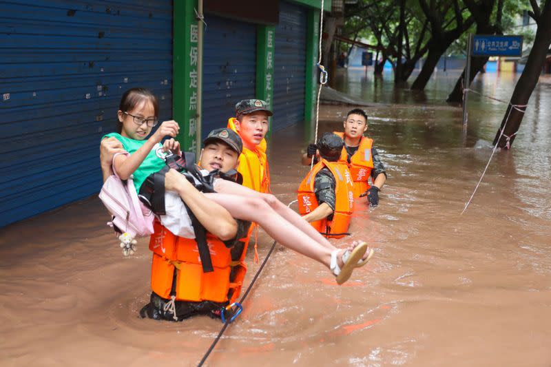 Paramilitary police officer evacuates a resident while he is wading through floodwaters following a heavy rainfall in Wanzhou of Chongqing